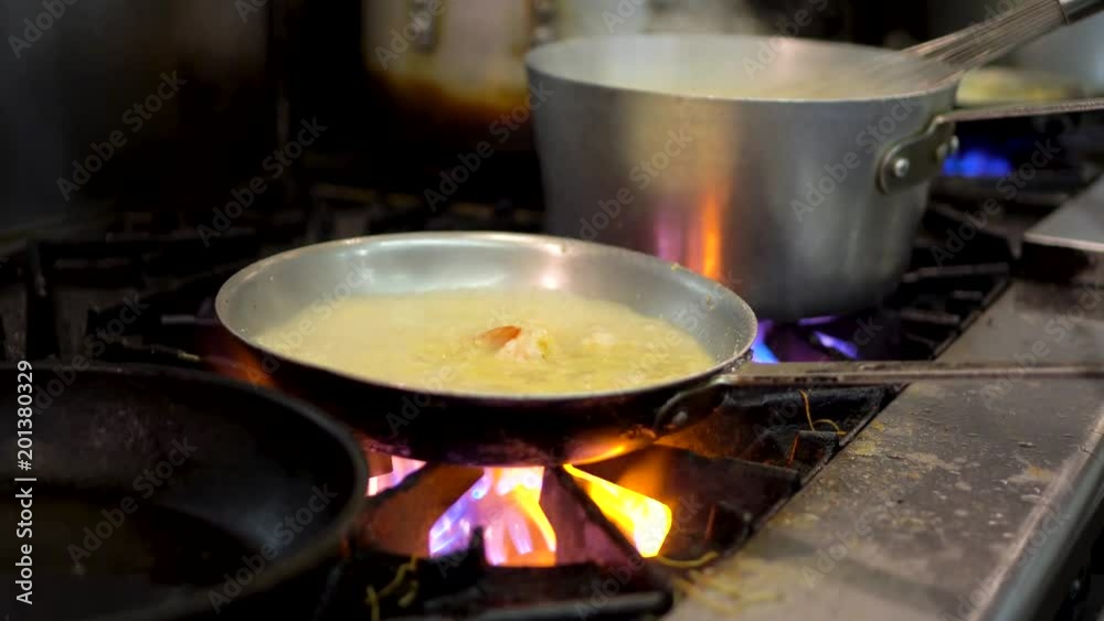 Low angle closeup of shrimp cooking in a chef’s kitchen in a pan on a fire. Low angle closeup of shrimp cooking in a chef’s kitchen in a pan on a fire.