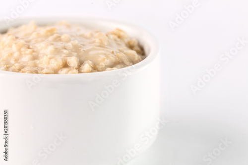 breakfast: oatmeal porridge in white bowl on white background. Isolated