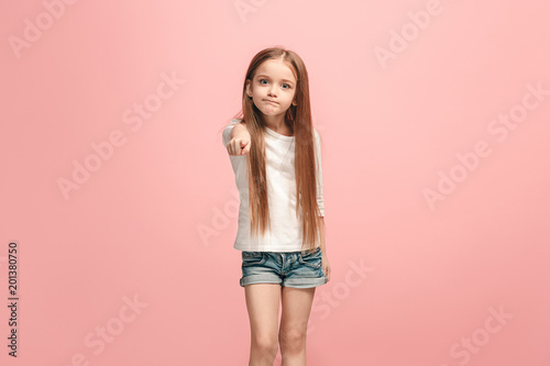 The teen girl pointing to you  half length closeup portrait on pink background.