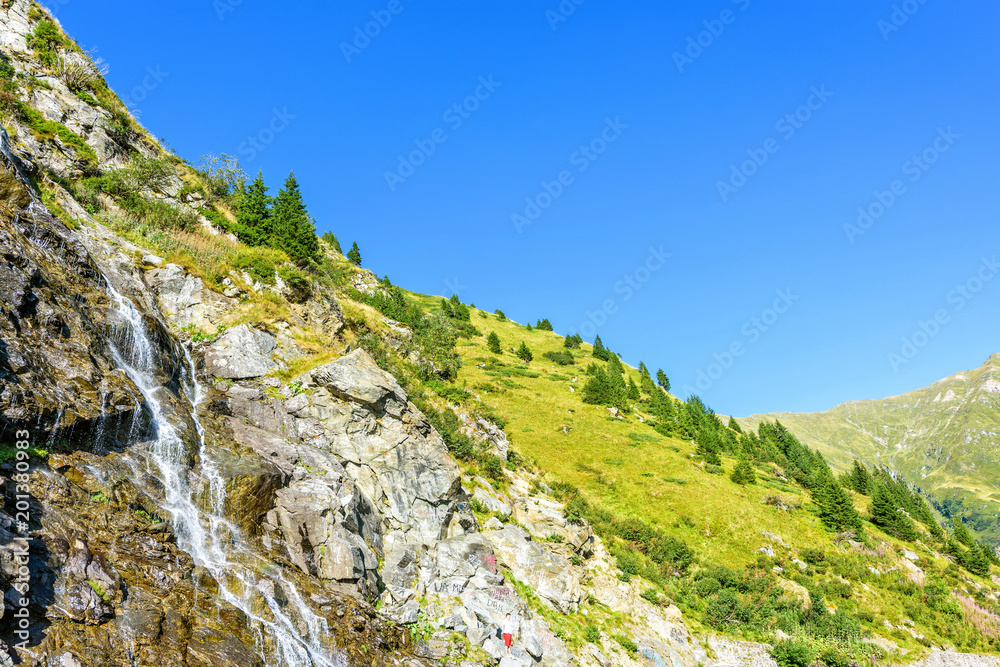 Daylight view to waterfall on the side of road in the Carpathian Mountains
