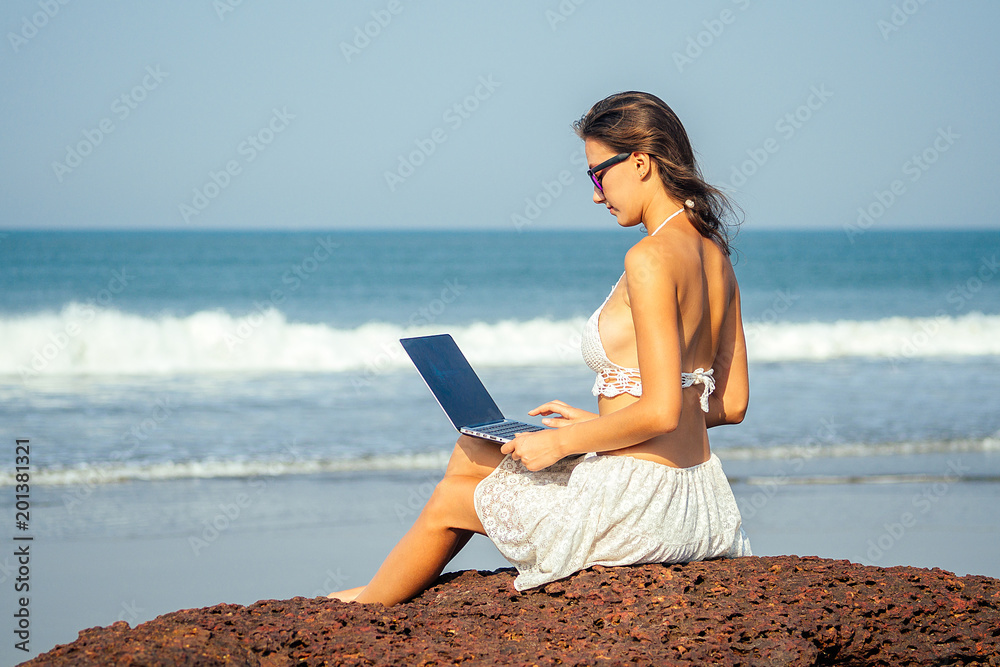 portrait of a young and beautiful freelancer girl running on the beach with a laptop. woman businessman on vacation. concept of freelancing and work