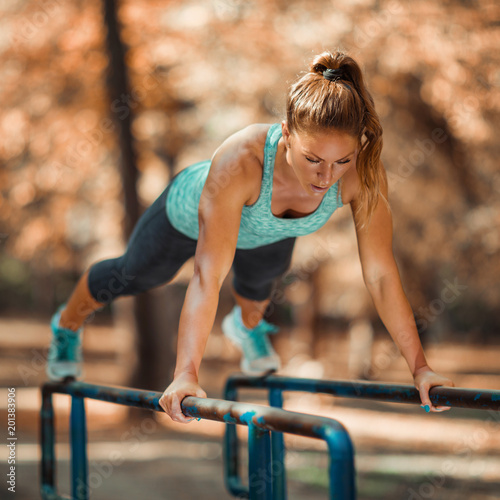 Woman Exercising on Parallel Bars Outdoors in The Fall