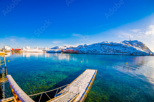 Outdoor view of amazing nature landscape with turquoise water and sunny day in blue sky with a floating structure in the lake and huge mountain covered with snow in Svolvaer photo