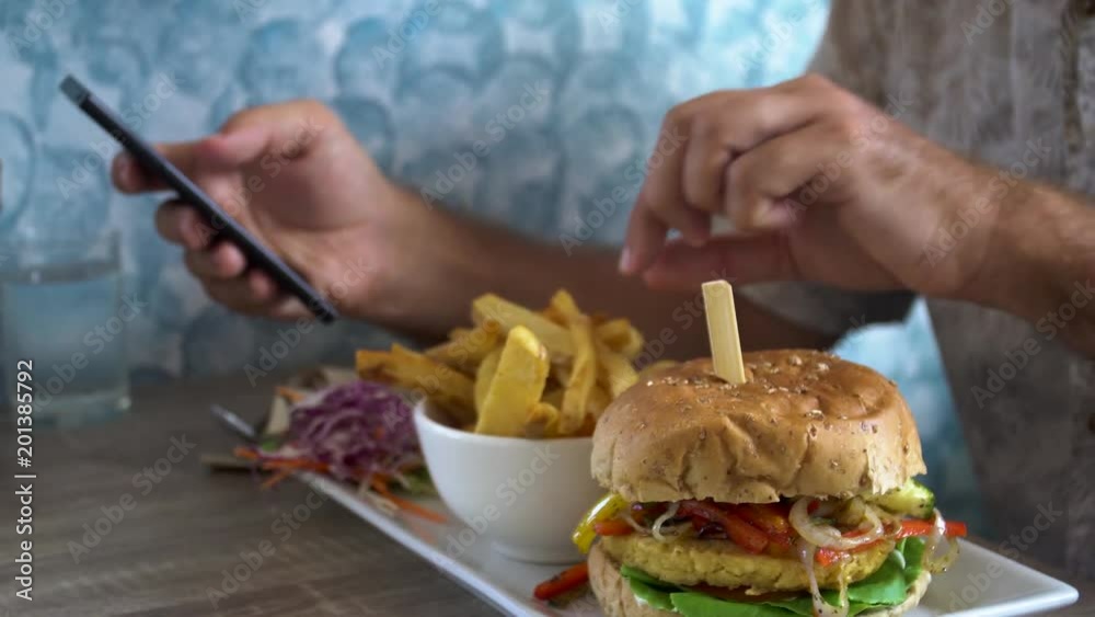 Man Eating Burger with French Fries and Chatting on Phone Man Eating Burger with French Fries and Chatting on Phone