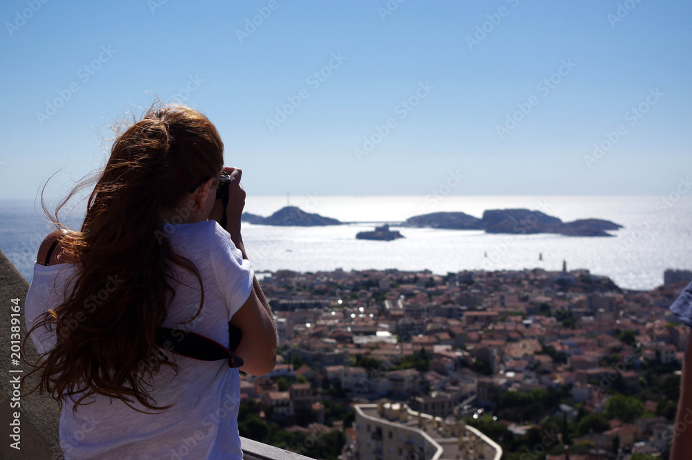 femme photographiant Marseille et les iles du frioul depuis Notre-dame-de-la-garde