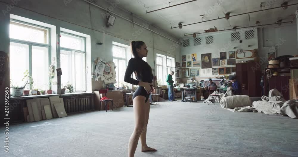 Pretty young girl dancing contemporary dance in the spacious big art studio. Woman trains the flexibility of her body