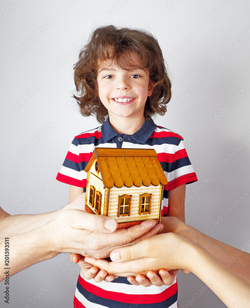 Many hands hold a toy house. Boy dream of getting your own home in the