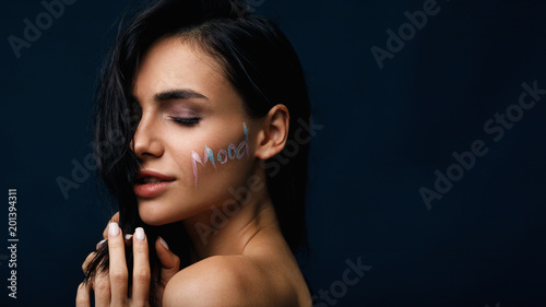Studio portrait of a sensual woman with word  Mood  on her face