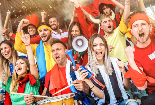 Football supporter fans friends cheering and watching soccer cup match at intenational stadium - Young people group with multicolored t-shirts having excited fun on sport world championship concept photo