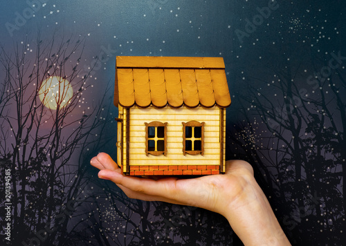 Small wooden toy house in handa on a dark background photo