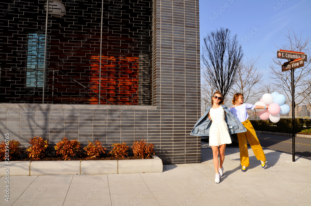 Obraz premium Fashionable urban girls wearing trendy outfit with balloons walking on New York City street.