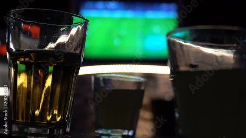 Blurred image of sport bar with TV and drinks in foreground