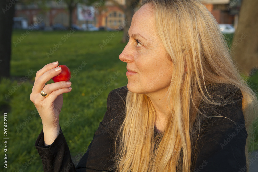 Mujer pensativa sujeta un tomate fresco en su mano. Alimentación sana. Mujer pensativa sujeta un tomate fresco en su mano. Alimentación sana.