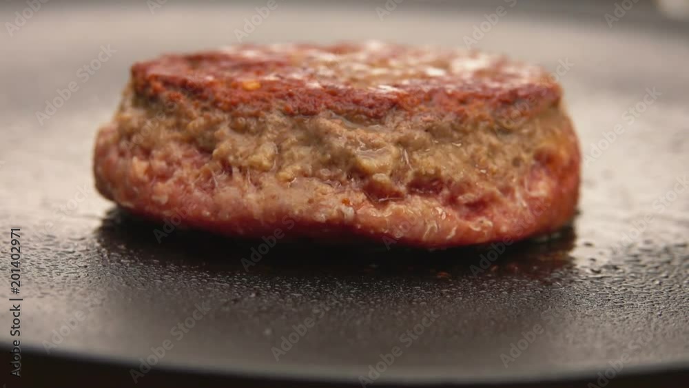 Burger flipped on the stone grill with kitchen spatula Burger flipped on the stone grill with kitchen spatula