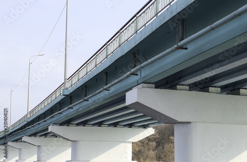 Piles under the bridge. Long concrete bridge across a wide river on a Sunny day