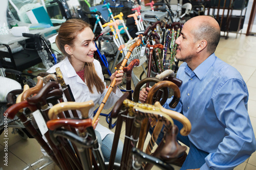 Mature man asking  smiling female doctor about walking sticks © JackF