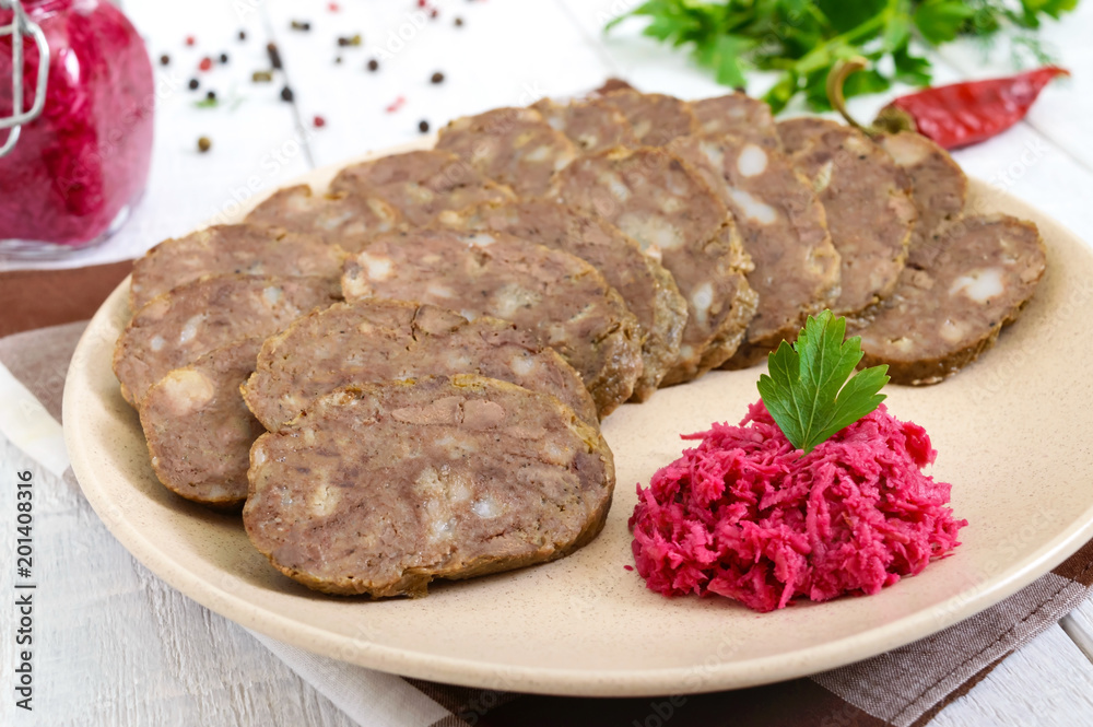 Home made dietary sausage from the liver on a white wooden table. Sausage cut into pieces on a plate with horseradish sauce. Home made dietary sausage from the liver on a white wooden table. Sausage cut into pieces on a plate with horseradish sauce.