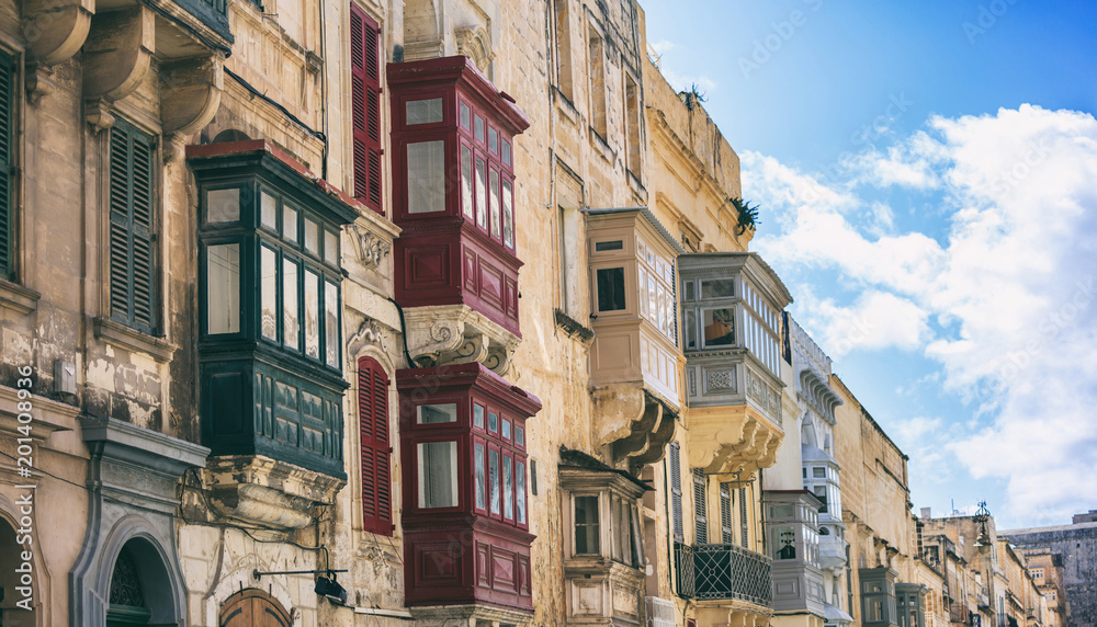 Fototapeta premium Malta, Valletta, building facade with covered balconies, with blue sky background, perspective view