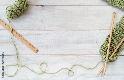 Knitting needles, yarn and ruler on a whitewashed wood table