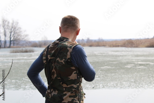 The man stares into the distance while standing on the shore of the la