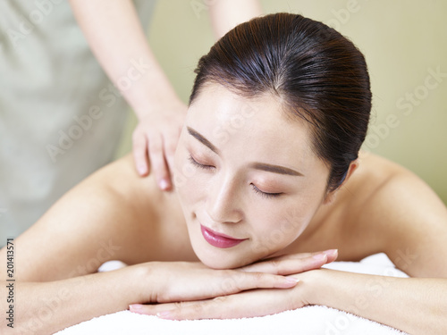 beautiful young asian woman receiving massage in spa salon