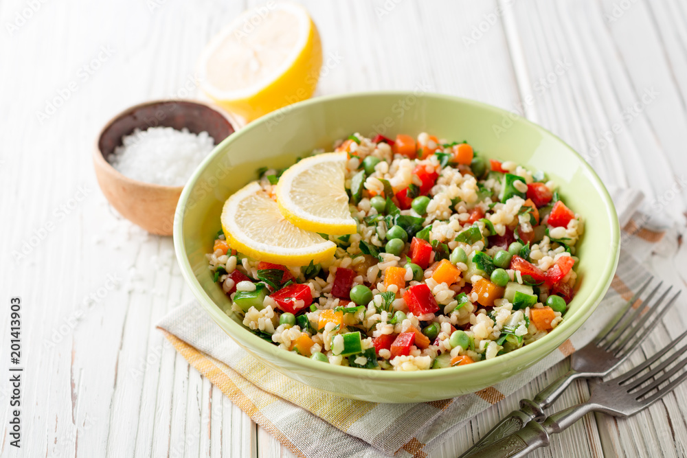 Fresh salad with bulgur and vegetables on white wooden table Fresh salad with bulgur and vegetables on white wooden table