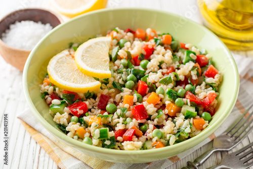 Fresh salad with bulgur and vegetables on white wooden table