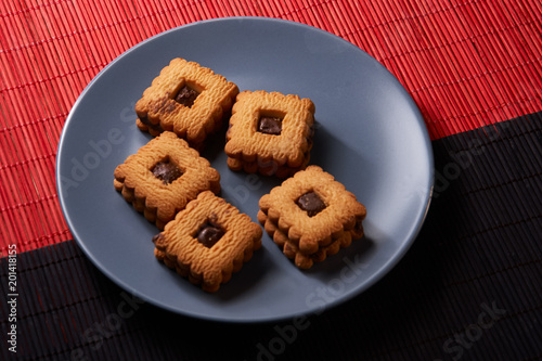 Chocolate sand chip cookies stacked up on a plate, ready to be served on blue plate photo