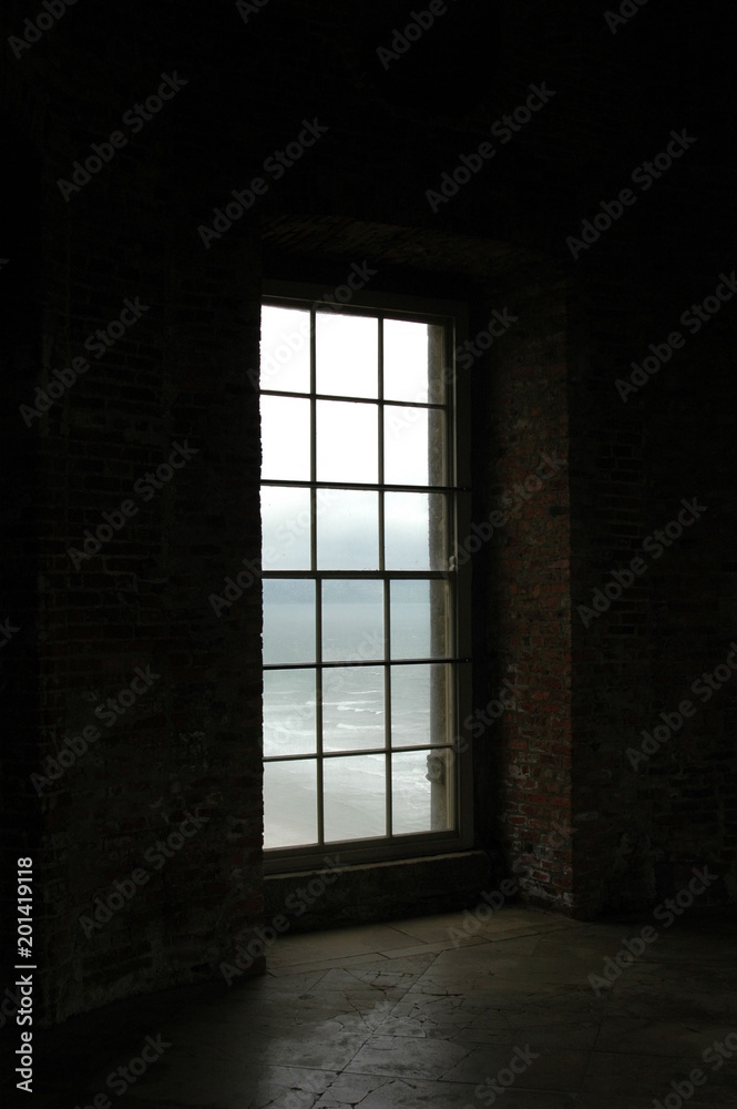 Light projects through a window unto a stone floor