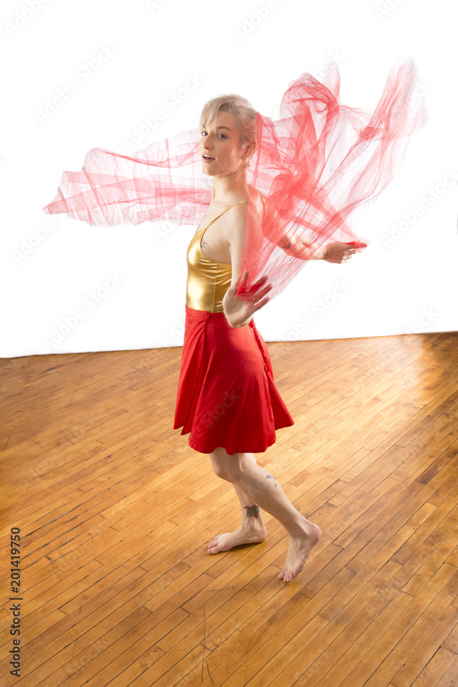 Young woman dancer twirling pink chiffon fabric in the studio. Young woman dancer twirling pink chiffon fabric in the studio.