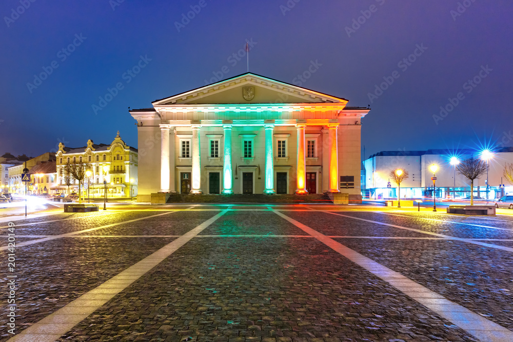 Fototapeta premium Town Hall Square in Old Town illuminated by the colors of the national Lithuanian flag at night of Vilnius, Lithuania, Baltic states.