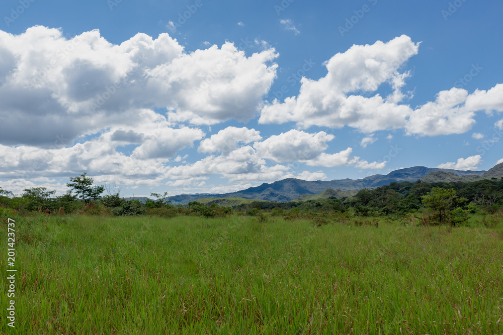 open field view, a break along the trail, mountains and clouds composing a stunning landscape