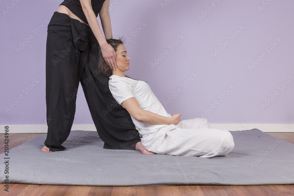 Young woman lying while enjoying stretching and the acupressure techniques of traditional Thai massage at spa and wellness center Young woman lying while enjoying stretching and the acupressure techniques of traditional Thai massage at spa and wellness center