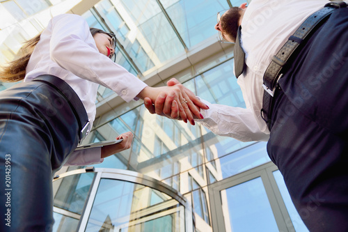 Handshake of a man and a woman against a multi-storey office building. Make a deal. Friendly relations. Office staff