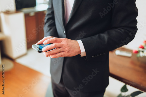 A man in a suit is holding a smartphone. Business and technology. Mobile phone.