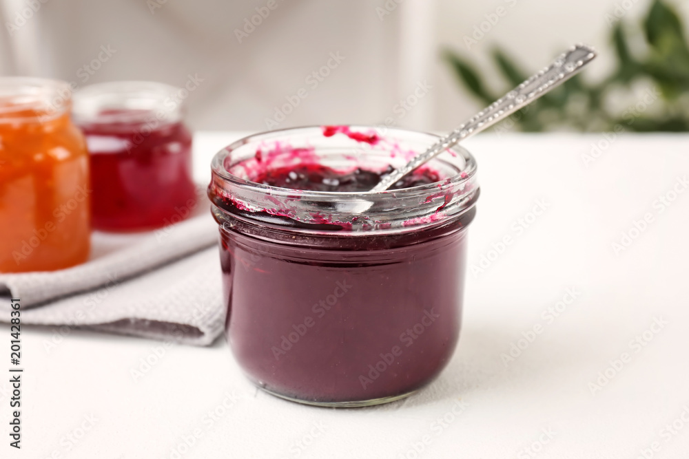 Jar with sweet jam on white table
