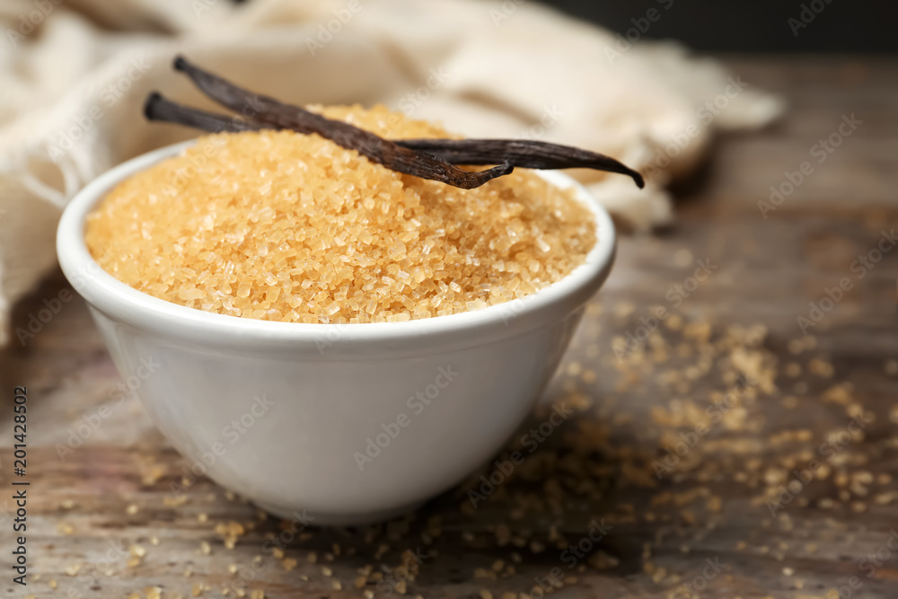 Bowl of aromatic vanilla sugar and sticks on wooden background Bowl of aromatic vanilla sugar and sticks on wooden background