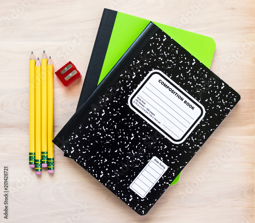 back to school-4 yellow pencils, one red pencil sharpener and two notebooks on a wooden desk