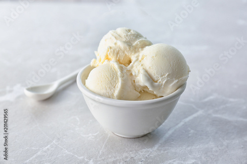 Bowl with tasty vanilla ice cream on light background