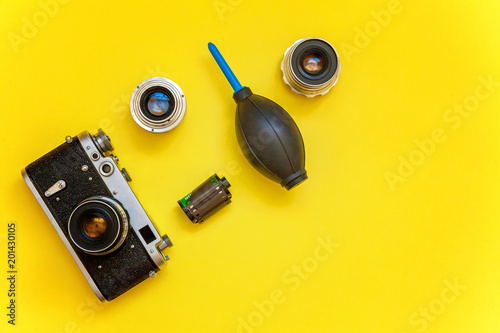 Vintage film photo camera lens film roll and accessories on yellow colourful trendy modern fashion pin-up background. Technology development photographer hobby classic memory trip concept. Top View
