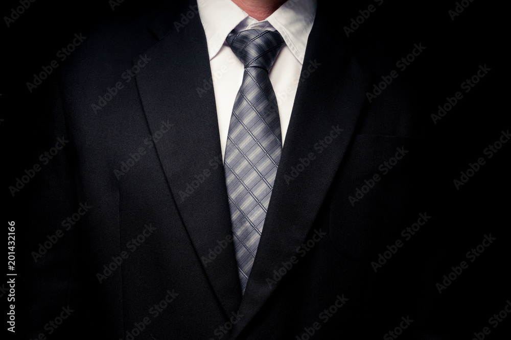 Close up of man in black suit, shirt and tie on black background Close up of man in black suit, shirt and tie on black background