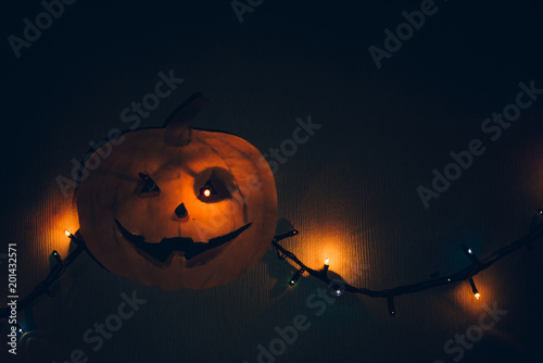 A paper pumpkin with a flashing garland in place of the eyes, hanging on the wall. A horrible template for Halloween.