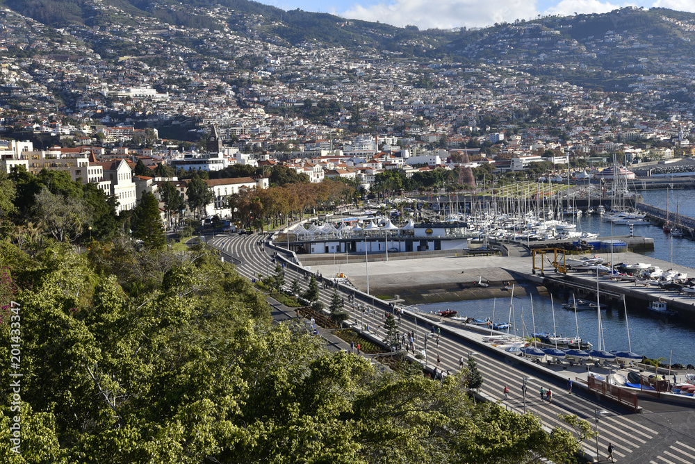 View over the city of Funchal.Funchal is the Capital of the island of Madeira. The distinctive houses and roofs seem to pile on top of each other as the land rises steeply from the Atlantic Ocean.
