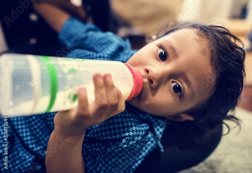 Young Indian boy drinking milk from bottle photo