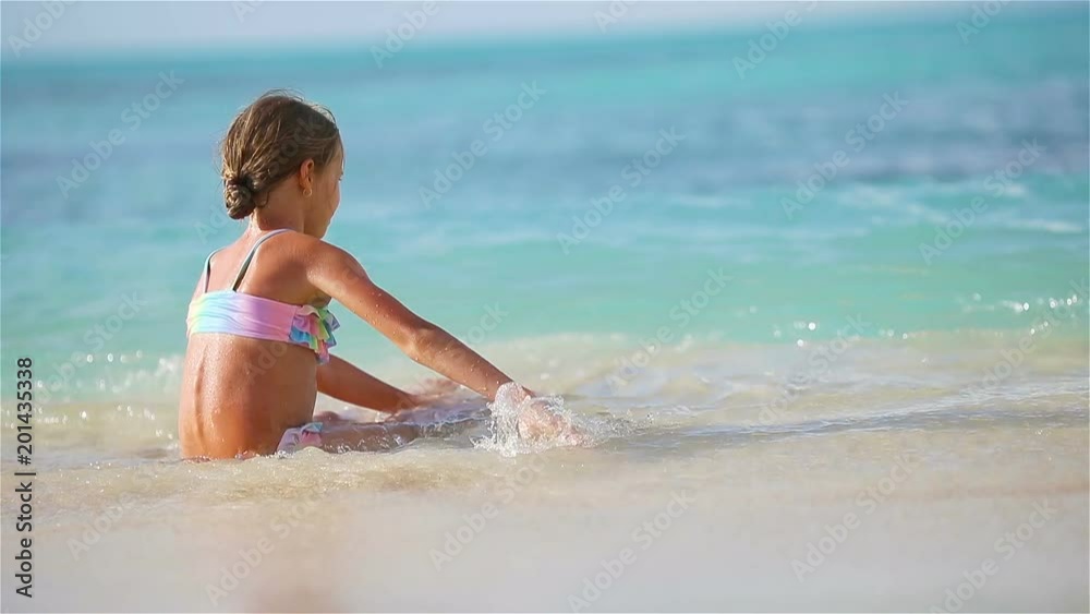 Adorable little girl at beach having a lot of fun in shallow water