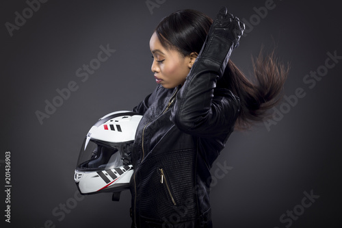Obraz na plátně Black female motorcycle rider or race car driver wearing a racing helmet and leather jacket