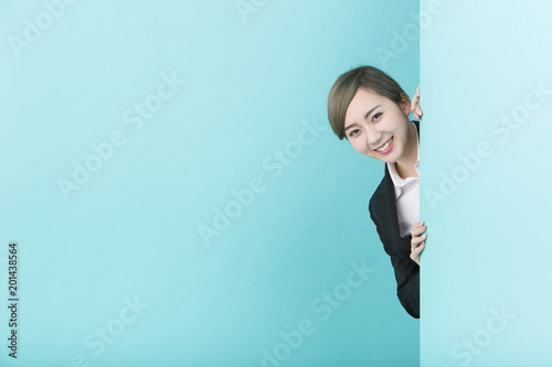 壁から顔を出して微笑むスーツの女性