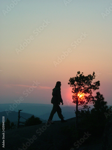Silhouette of a man on mountain top at sunset background.