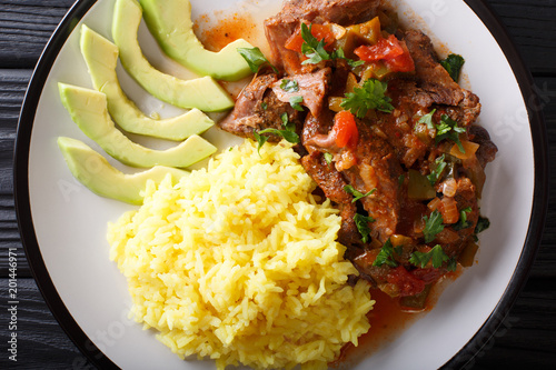 Seco de chivo is goat stew with yellow rice and avocado close-up on a plate. Horizontal top view