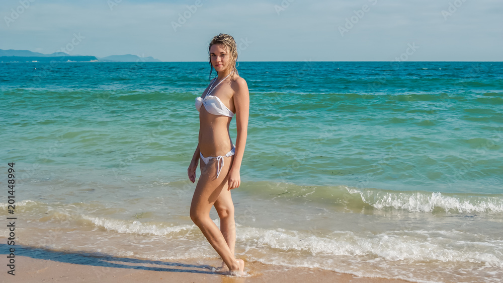 Pretty young girl dressed up in white swimwear on the beach
